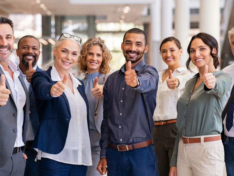 Photographie d'une équipe d'employés souriant, levant un pouce en l'air face à l'appareil photo.