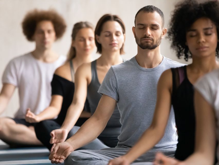 Photograhie d'un groupe de personnes en pleine méditation, assis les jambes en lotus.