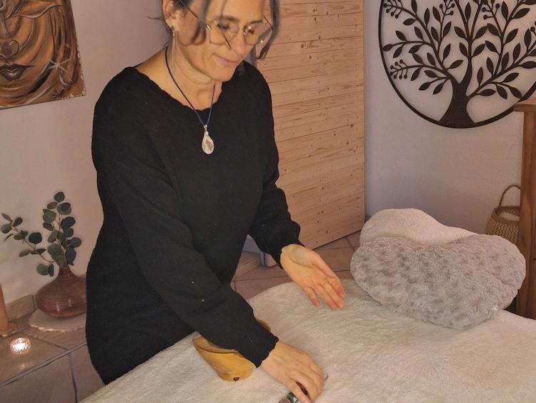 Photographie de Nathalie alignant des pierres sur un lit de massage.