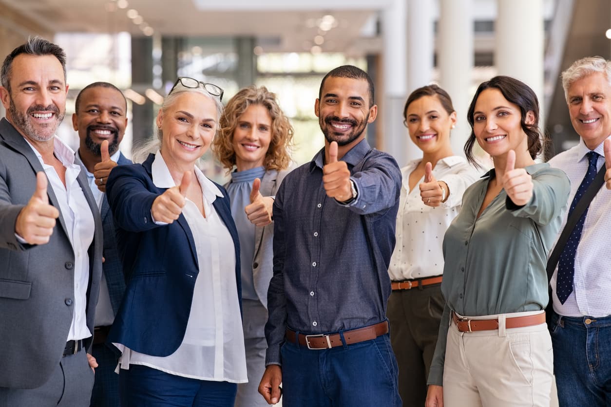 Photographie d'une équipe d'employés souriant, levant un pouce en l'air face à l'appareil photo.