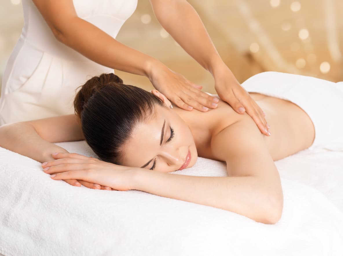 Photograhpie d'une femme allongée sur le ventre sur une table de massage en train de se faire masser le dos.