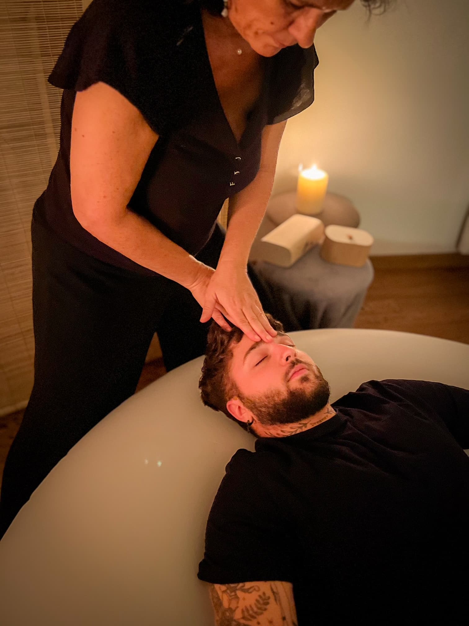 Photographie du buste d'un homme allongé sur un coussin d'air, se faisant masser le visage par Nathalie.