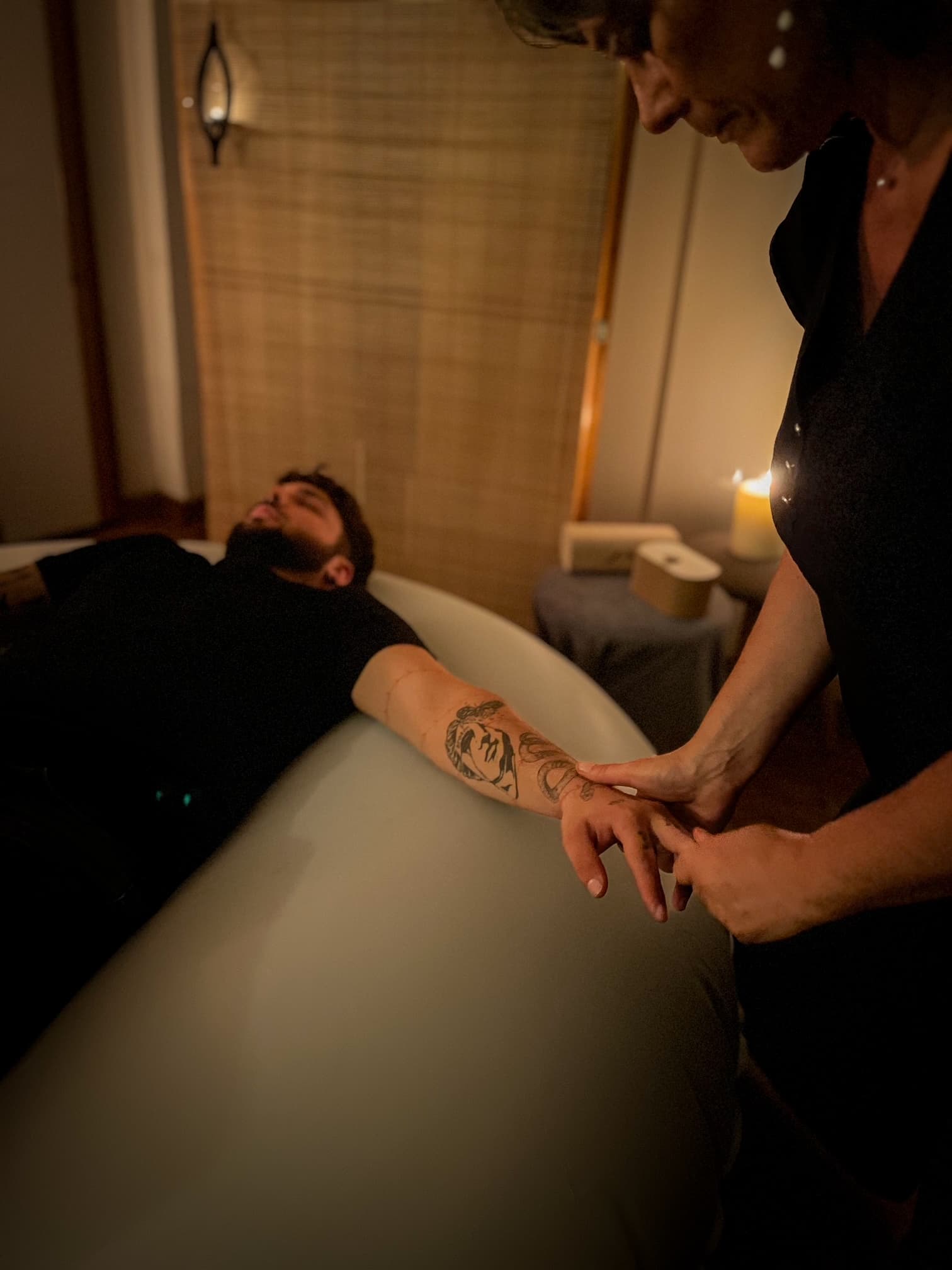 Photographie d'un homme allongé sur un coussin de massage en train de se faire masser les doigts par Nathalie.